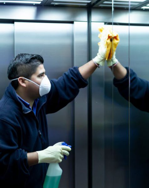 coronavirus. cleaning staff disinfecting elevator to avoid contagion