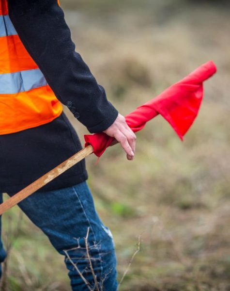 a boy with a red flag in his hands is responsible for the safety of a car rally.