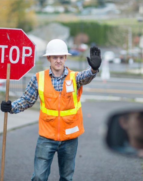 Flagger holds up stop sign for traffic in construction zone