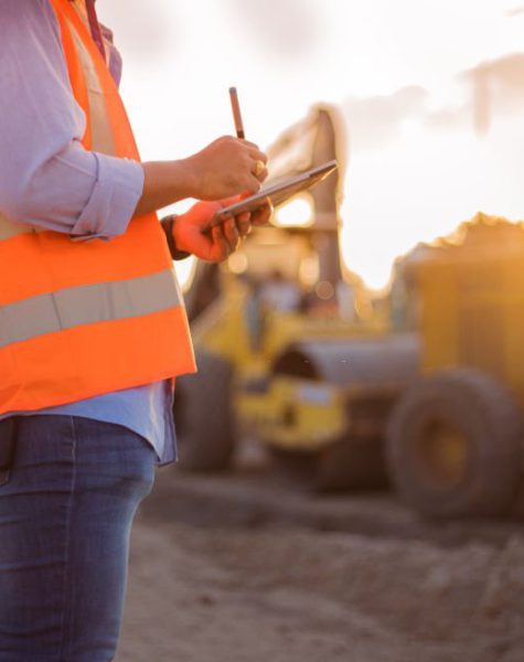 Asian engineer with hardhat using  tablet pc computer inspecting and working at construction site